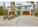 Two-story home with double wooden garage doors and landscaped front yard at 238 Oak Ave, Anna Maria, FL 34216