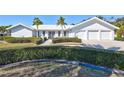 White house with a three-car garage and lush landscaping at 6851 Country Lakes Cir, Sarasota, FL 34243