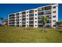 Well-maintained condo building featuring screened balconies, a vibrant green lawn, and beautiful landscaping at 757 Beach Rd # 300, Sarasota, FL 34242