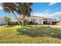 Well-kept home featuring a green lawn, palm trees, and convenient carport at 1716 Forest Rd, Venice, FL 34293