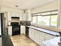 Modern kitchen with white cabinets, stainless steel appliances, and a large window at 2040 Pine Ridge Dr, Clearwater, FL 33763