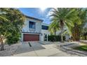 Contemporary two-story home featuring a modern facade, wood garage door, and tropical landscaping at 2434 Wood St, Sarasota, FL 34237