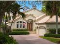 Two-story house with brick driveway, lush landscaping, and a three-car garage at 601 Weston Pointe Ct, Longboat Key, FL 34228