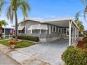 Gray manufactured home with carport, landscaping, and American flag at 62 Pelican S Dr, Oldsmar, FL 34677