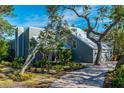 Gray house with a metal roof, landscaping, and a brick paver driveway at 716 Tropical Cir, Sarasota, FL 34242