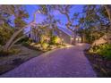 House exterior at dusk, showcasing landscaping and a brick driveway at 716 Tropical Cir, Sarasota, FL 34242