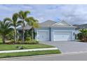 House exterior with light blue walls, two-car garage, and palm trees at 13619 Old Creek Ct, Parrish, FL 34219
