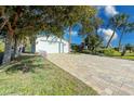 Charming home featuring a two-car garage and a brick-paved driveway, framed by mature trees and lush landscaping at 309 South Dr, Nokomis, FL 34275