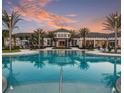 Resort-style pool with clubhouse at sunset, lush landscaping at 8612 Sundance Loop, Sarasota, FL 34238