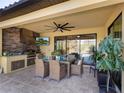 Covered outdoor kitchen with built-in grill, seating area, and ceiling fan at 17459 Hickok Belt Loop, Bradenton, FL 34211