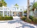 Inviting entryway with a pergola and tropical landscaping at 18 N Casey Key Rd, Osprey, FL 34229