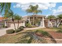 Beige house with tile roof, two-car garage, and lush landscaping at 5112 White Ibis Dr, North Port, FL 34287