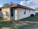 Neutral-toned home exterior shows corner, windows, and AC unit with an attached back door and partial view of a neighboring house at 22389 Elmira Blvd, Port Charlotte, FL 33952