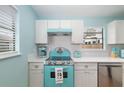 Retro teal stove and white cabinets in bright kitchen at 3200 Tobero Ln, Sarasota, FL 34235