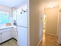 Efficient kitchen featuring white cabinets and appliances, next to hallway leading to bathroom at 5918 Palm Ln # C33, Bradenton, FL 34207