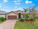 One-story house with a brown garage door, lush landscaping, and a paver driveway at 7409 Chester Trl, Bradenton, FL 34202