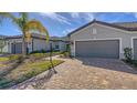 Exterior view of a house with a two-car garage, walkway, and palm trees in the front at 7590 Summerland Cv, Bradenton, FL 34202