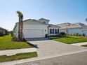 Beautiful exterior view of a one-story home with lush green grass, a brick driveway, and a 2-car garage at 15610 San Lazzaro Ave, Bradenton, FL 34211