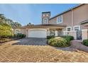 Tan two-story townhome with white garage door, brick driveway, and lush landscaping at 1719 Starling Dr # 1719, Sarasota, FL 34231