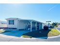 Tan single-wide manufactured home with covered carport and patio furniture at 3214 Pink Oak Ter, Sarasota, FL 34237