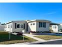 Tan single-wide manufactured home with covered carport and landscaping at 3214 Pink Oak Ter, Sarasota, FL 34237