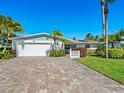 Single-story home with a white exterior, paver driveway, and tropical landscaping at 5303 Coral Blvd, Bradenton, FL 34210