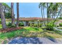 Pleasant single-story home with neatly kept lawn, mature trees and shrubbery under a clear blue sky at 5376 Royal Palm Ave # 5376, Sarasota, FL 34234