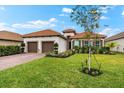 Inviting one-story home with lush landscaping, a two-car garage, and a red-tiled roof at 10120 Carnoustie Pl, Bradenton, FL 34211