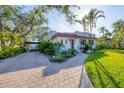 Paver driveway leading to a white home with a red tile roof, surrounded by lush tropical landscaping at 1864 Clematis St, Sarasota, FL 34239