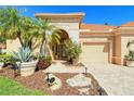 Front entry with arched doorway, landscaping, and a three-car garage at 5118 Chateau Ct, Sarasota, FL 34238