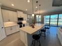 Modern kitchen with white cabinets, center island, and stainless steel appliances at 649 Maraviya Blvd, Nokomis, FL 34275