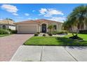 Single-story home features a beige exterior, lush landscaping, and a brick driveway at 6841 74Th Street E Cir, Bradenton, FL 34203