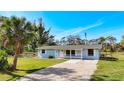 Inviting single-story home featuring a well-maintained lawn, a gravel driveway, and a cozy front porch at 712 N Elm St, Englewood, FL 34223