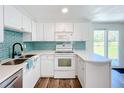 Nicely updated kitchen with white cabinetry, stylish backsplash, and stainless steel sink at 712 N Elm St, Englewood, FL 34223