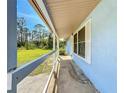 View from the porch of home with white wood and blue wall paint, overlooking a well manicured green yard at 712 N Elm St, Englewood, FL 34223