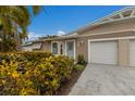 Tan house with white garage doors, landscaping, and palm trees at 205 82Nd St # East, Holmes Beach, FL 34217