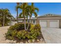 Tan house with white garage doors, landscaping, and palm trees at 205 82Nd St # East, Holmes Beach, FL 34217