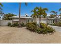 Tan house with white garage doors, landscaping, and palm trees at 205 82Nd St # East, Holmes Beach, FL 34217