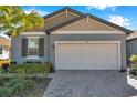 Two-tone home with gray and beige siding, white garage door, and palm trees at 3747 Laughing Dove Ave, Sun City Center, FL 33573