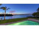 Backyard pool with views of the water at dusk, surrounded by well-maintained landscaping and a spacious patio at 400 N Washington Dr, Sarasota, FL 34236