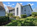 Exterior view of a two-story townhome showcasing lush landscaping, a screened balcony, and neutral paint at 6609 Stone River Rd # 206, Bradenton, FL 34203