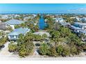 An aerial view showcasing waterfront homes along a canal, surrounded by lush trees at 9205 Gulf Dr, Anna Maria, FL 34216