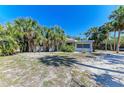 Charming single-story home with a white exterior, surrounded by lush palm trees and sandy grounds at 9205 Gulf Dr, Anna Maria, FL 34216