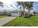 Front view of tan house with white garage door and palm trees at 1364 Berkshire Ct, Venice, FL 34292