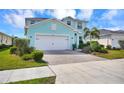 Charming two-story home with a light blue exterior, two-car garage, and beautifully landscaped front yard at 17395 Palmetto Pass Ln, Punta Gorda, FL 33982