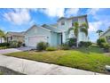 Charming two-story home with a light blue exterior, two-car garage, and beautifully landscaped front yard at 17395 Palmetto Pass Ln, Punta Gorda, FL 33982