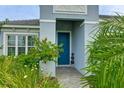 Inviting front entrance with blue door and lush landscaping at 2582 Wild Cherry Path, Sarasota, FL 34240