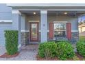 Inviting front porch with brick accents, red shutters, and an elegant glass front door, enhanced by lush landscaping at 5001 65Th E Ter, Ellenton, FL 34222