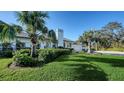 Home's exterior featuring a lush lawn, tropical landscaping, and a paved driveway leading to the garage at 1302 Roberts Bay Ln, Sarasota, FL 34242