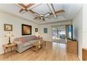 Comfortable living room with ceiling fan, wood flooring, and sliding doors to lanai at 1346 Queen Rd, Venice, FL 34293